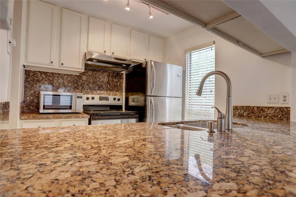 An alternate perspective of the kitchen highlights the elegant granite countertops and generous seating area for meals.