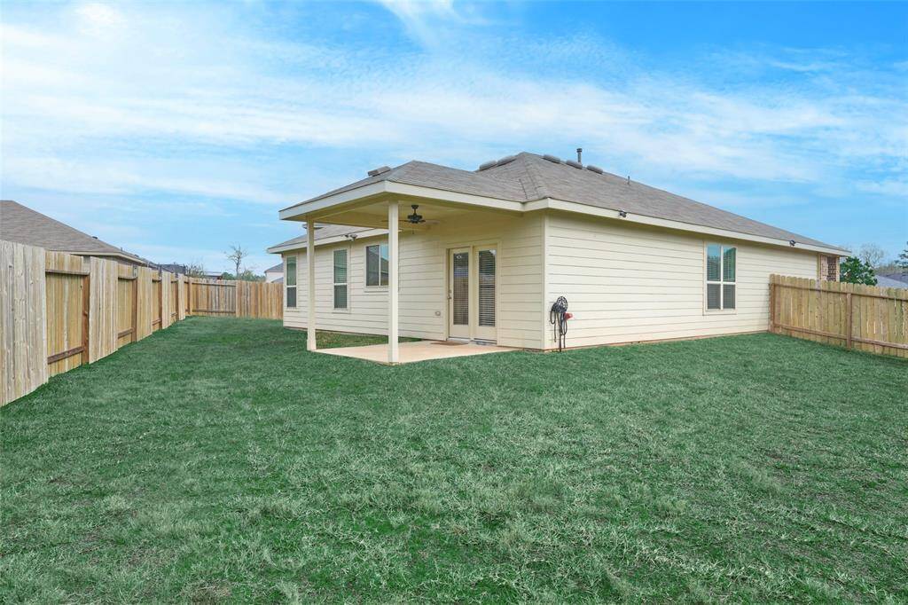 A single-story home with a spacious fenced backyard, featuring a covered patio area ideal for outdoor relaxation.