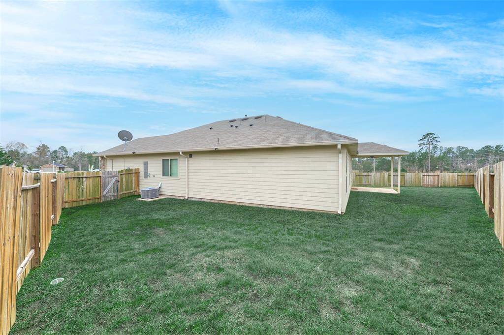 This photo showcases a spacious, fenced backyard with well-maintained grass, attached to a single-story home. There's a covered patio area, perfect for outdoor activities, and the property is bordered by wooden fencing for privacy.