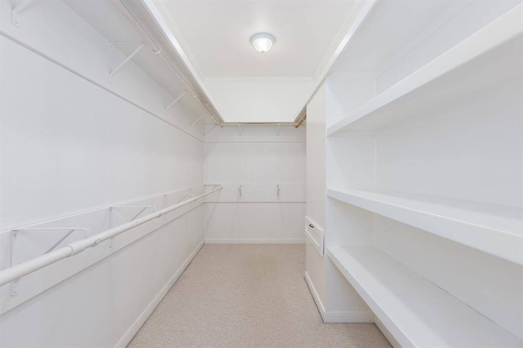 Spacious primary closet with tons of light, shelving and laundry shoot