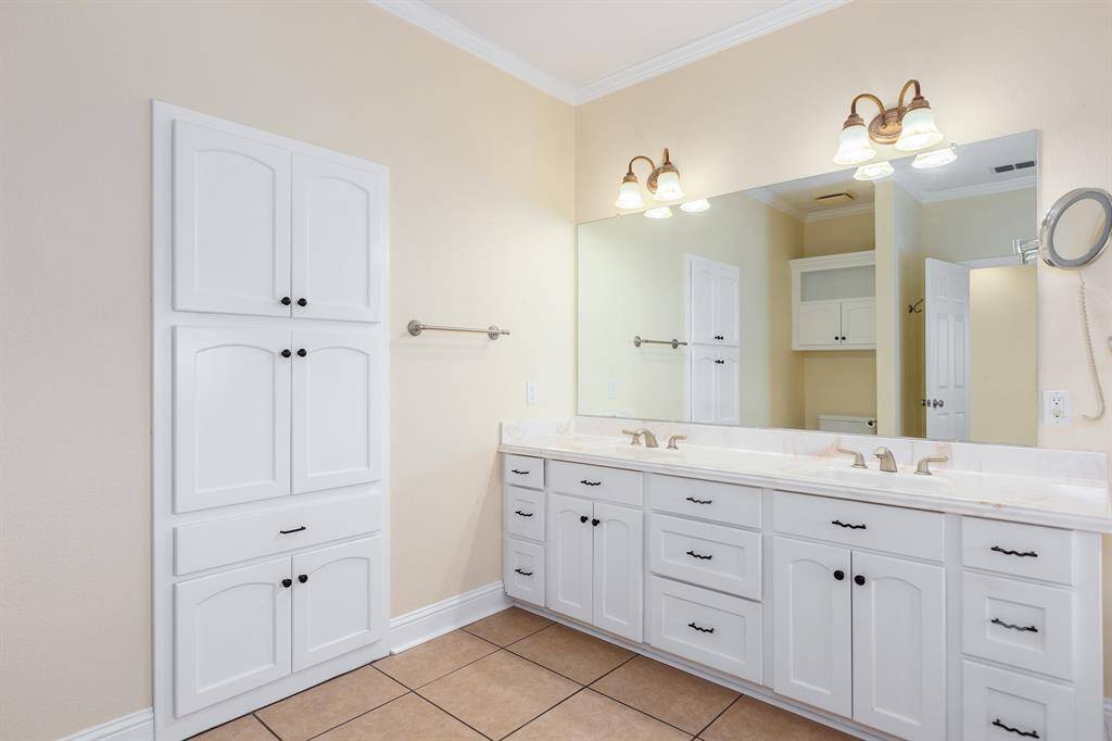 Expansive primary bathroom featuring ample storage with custom-built cabinetry