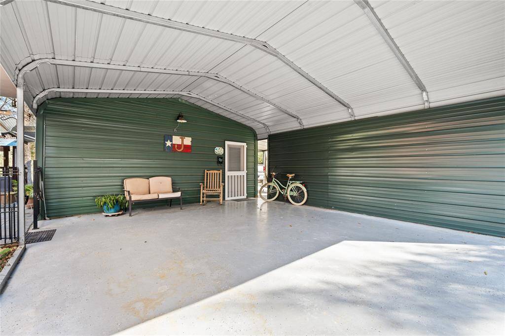 This photo shows a spacious, covered carport with a metal roof and green siding offering a functional and inviting outdoor area.