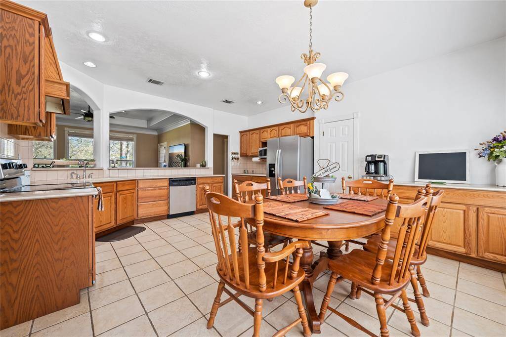 This spacious kitchen features wooden cabinetry, stainless steel appliances, and a central dining area. The open layout leads to a cozy living space, perfect for entertaining.