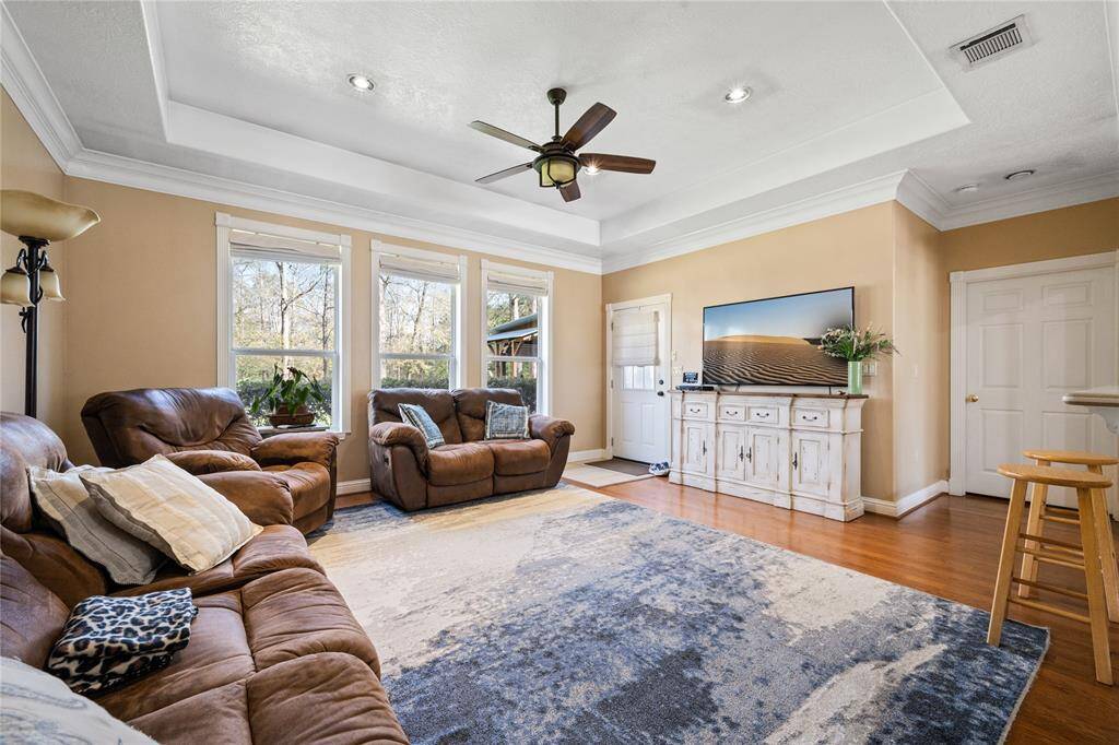 This cozy living room features large windows for natural light, recessed lighting, and warm wood flooring. Perfect for relaxing and entertaining.