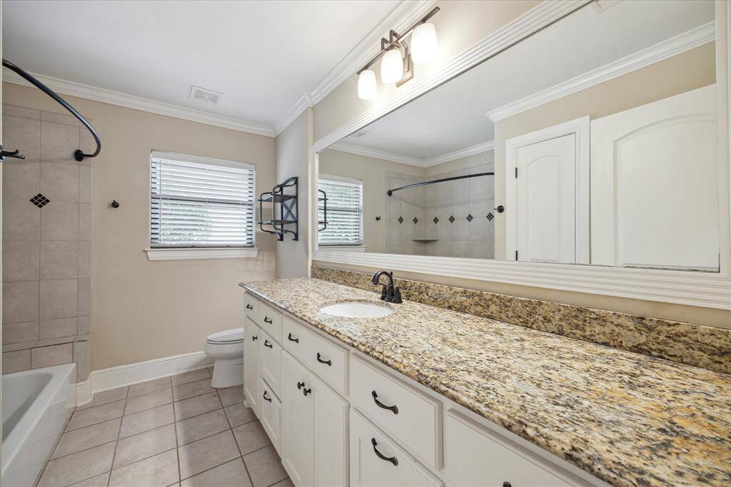 Secondary bathroom with granite countertops, tub/shower with tile surround.