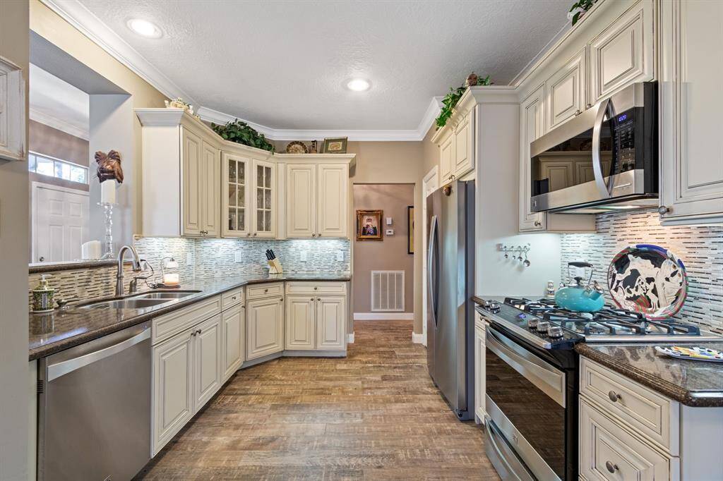 The totally updated kitchen features white (antiqued) cabinetry, stone back splash, abundant granite counters, stainless steel appliances, and recessed lighting. The cabinetry offers great storage along with a closet pantry next to the refrigerator. Please note that the counter-depth refrigerator also stays with the home.