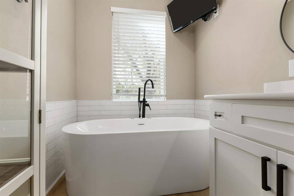 Upstairs master bath tub features jets, bubbler, and lights. Up top is a wall mounted TV. Window features blinds to let in sunlight while relaxing in the bath after a long day.