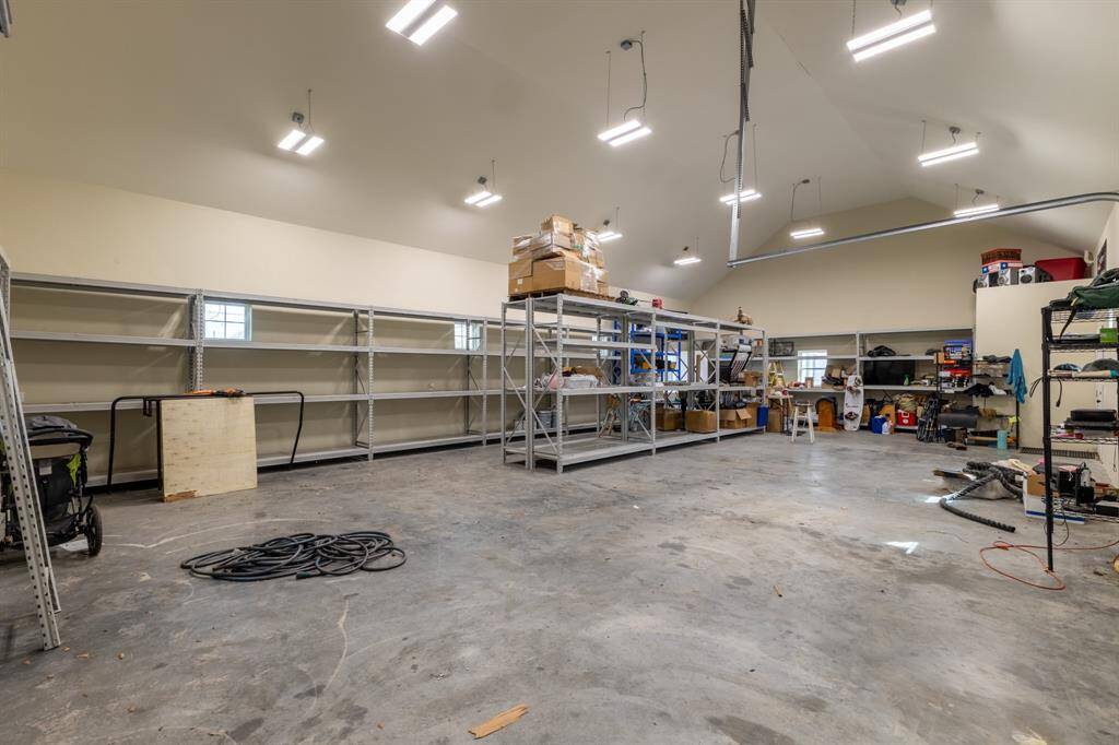 Large shop / garage / workout room / guest suite, fully sheet rocked with electrical outlets going down the walls and a half bath. Overhead lighting is split into 3 zones.