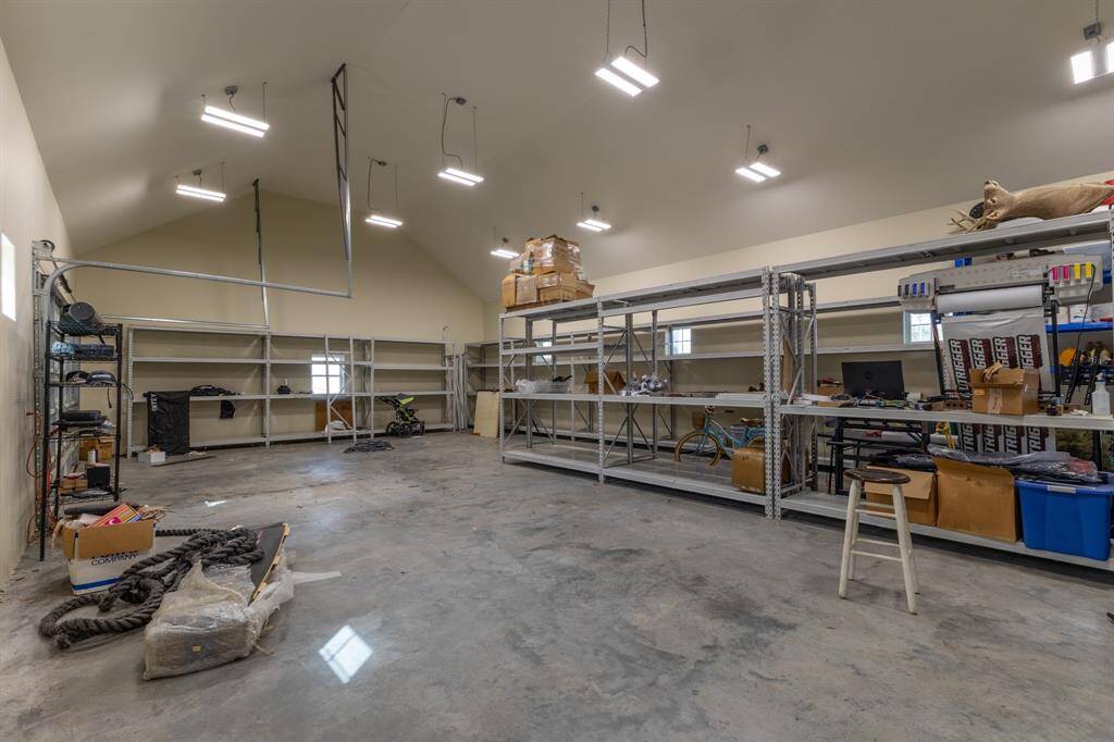 Large shop / garage / workout room / guest suite, fully sheet rocked with electrical outlets going down the walls and a half bath. Overhead lighting is split into 3 zones.