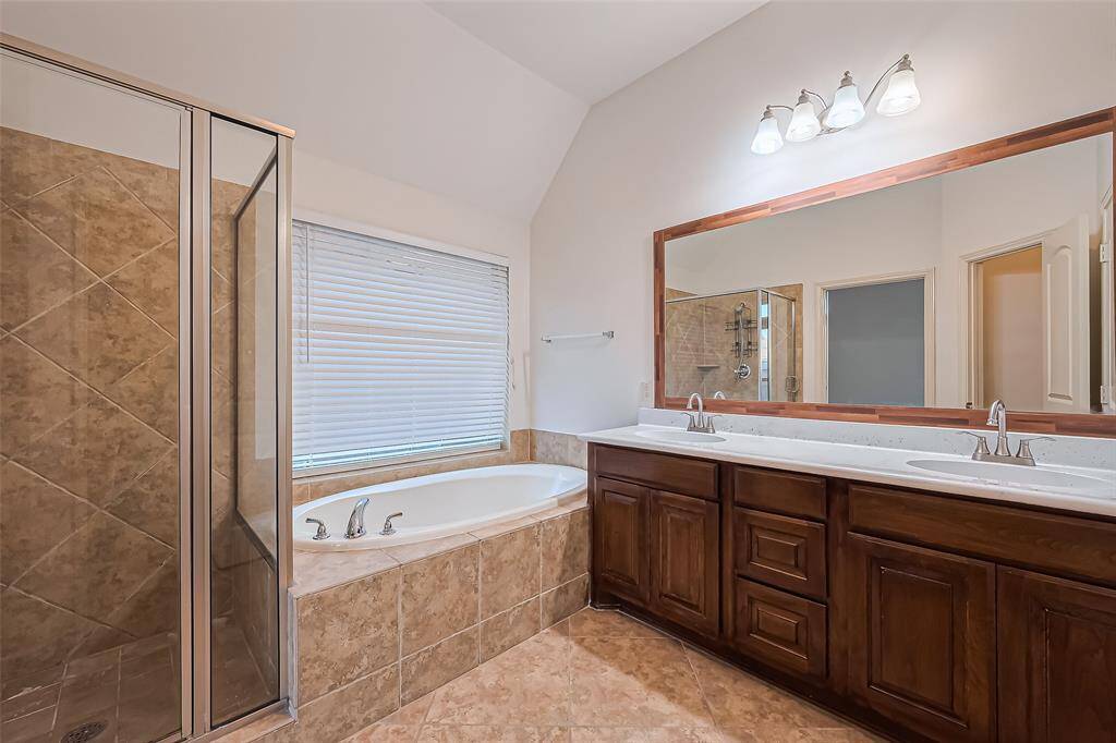 Spa-like primary ensuite with a dual vanity, fresh epoxy countertops, beautifully framed mirrors, a relaxing garden tub and glass enclosed shower.