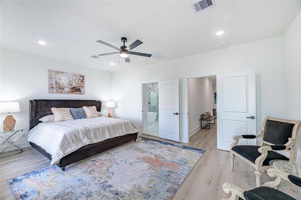 With light wood flooring, a ceiling fan, and lots of natural light, this huge bedroom has a contemporary look. With its lavish ensuite bathroom with a bathtub it's a chic and cozy haven.