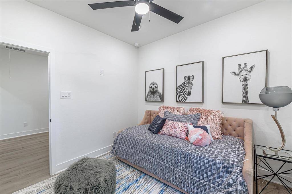 Cozy bedroom number 3 features a ceiling fan, light wood flooring, all creating a comfortable and inviting space.