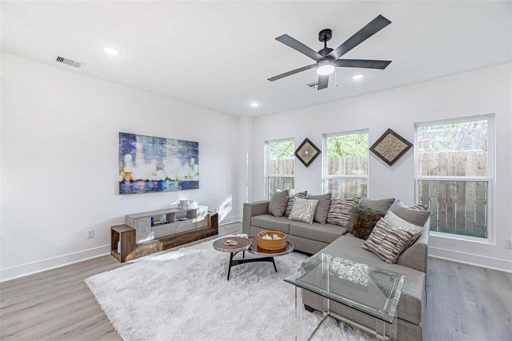 Large windows, an inviting open space characterize this light-filled, contemporary living space. The room's contemporary, the ceiling fan, and light wood floor all contribute to its cozy ambiance.