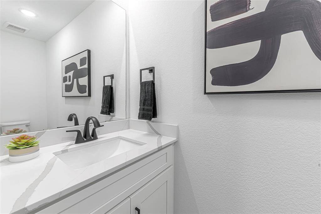 Modern half bath on first level with sleek matte black finishes.