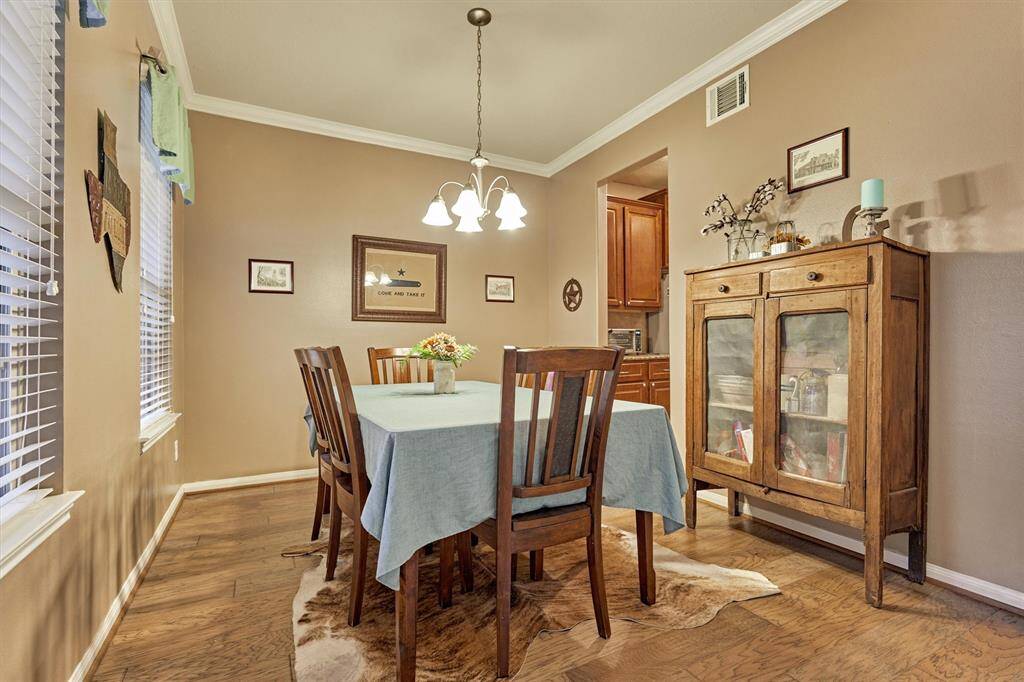 Spacious dining room with crown molding and rich wood flooring.