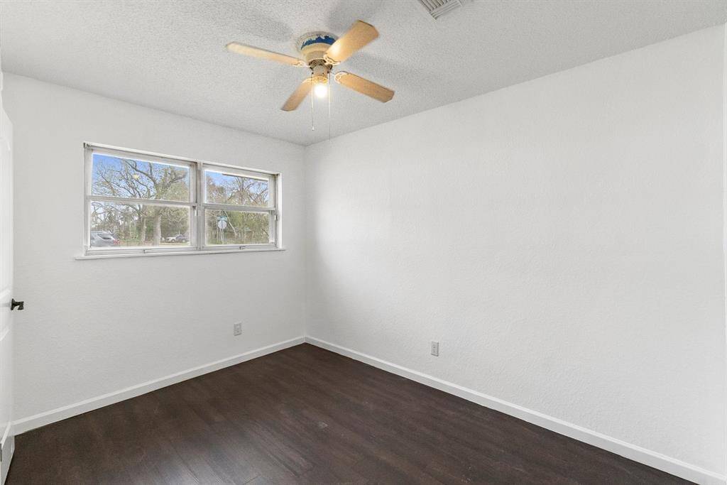 Here’s the other bedroom with fresh updates! The dark flooring pops against the crisp white walls, and that oversized window brings in great natural light. Whether you need a cozy retreat or a productive workspace, this room can do it all.