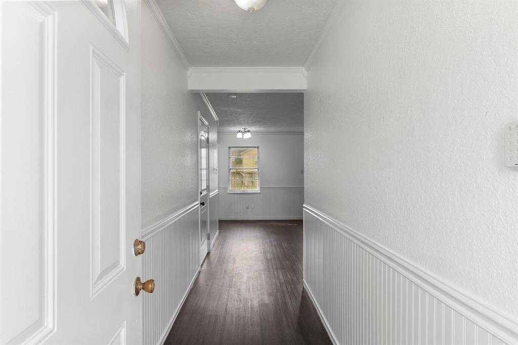 Step inside and take it in—fresh paint, crisp wainscoting, and a bright, airy feel that makes this space instantly inviting. That long hallway pulls you right in, leading straight to the action. This home has been cleaned up and refreshed, and it shows