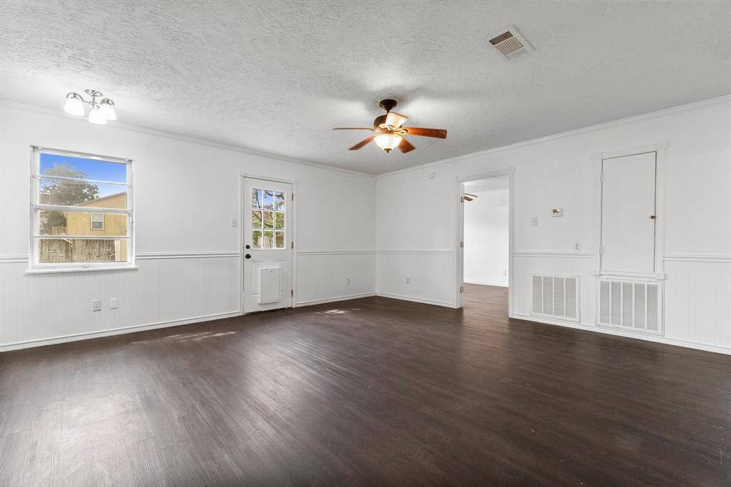 Now this is a living space! Freshly painted walls, sleek dark flooring, and tons of natural light make this room feel open and ready for anything. The back door gives you easy access to the yard, and that ceiling fan? Keeping things cool while you kick back and enjoy.