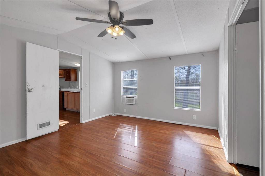 Spacious primary bedroom with abundant natural light, sleek  flooring, and a modern ceiling fan for comfort.