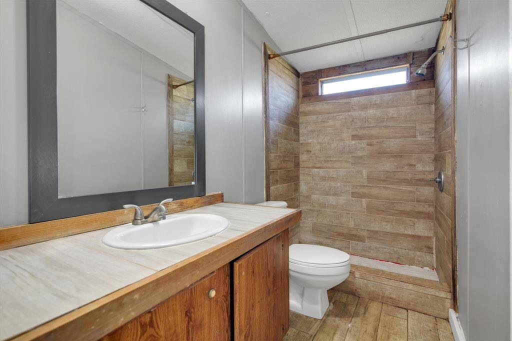 Modern and inviting, this bathroom features a stylish wood-accented shower, sleek fixtures, and ample counter space for all your essentials.