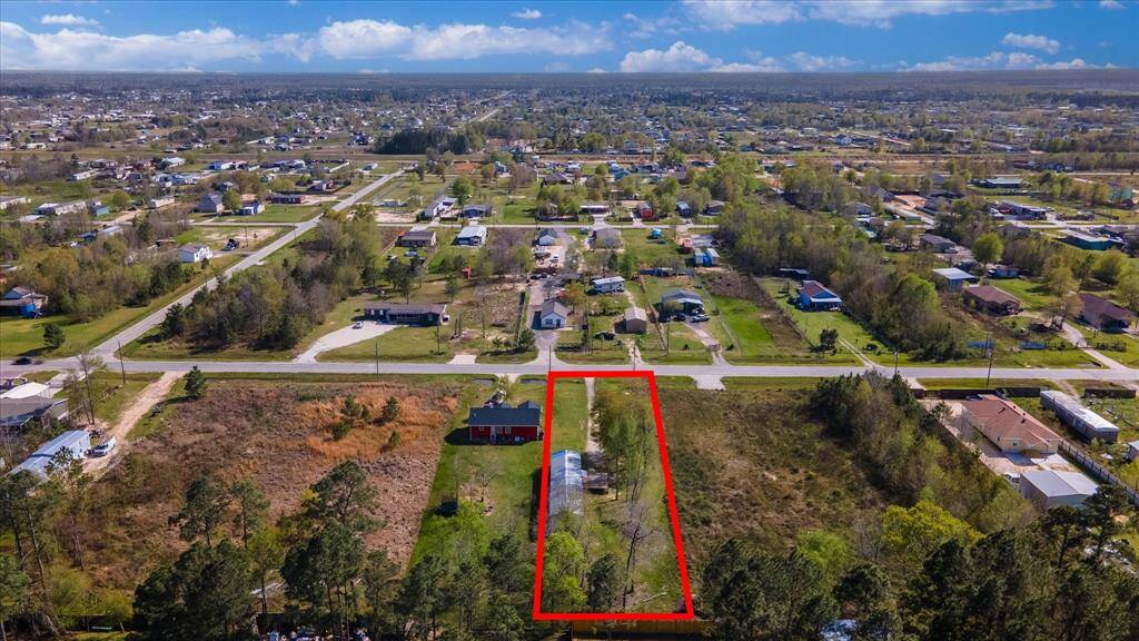 Large, rectangular plot of land outlined in red, situated in a suburban area with a mix of homes and open spaces. The property has a driveway and some trees, offering potential for development or landscaping. The surrounding neighborhood is well-established, with easy access to roads and nearby amenities.