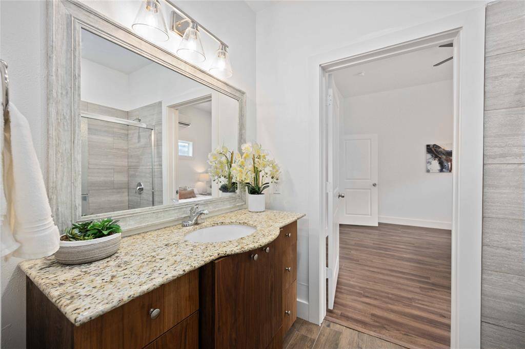 The primary bathroom features a gorgeous vanity under a framed mirror and elegant lighting.