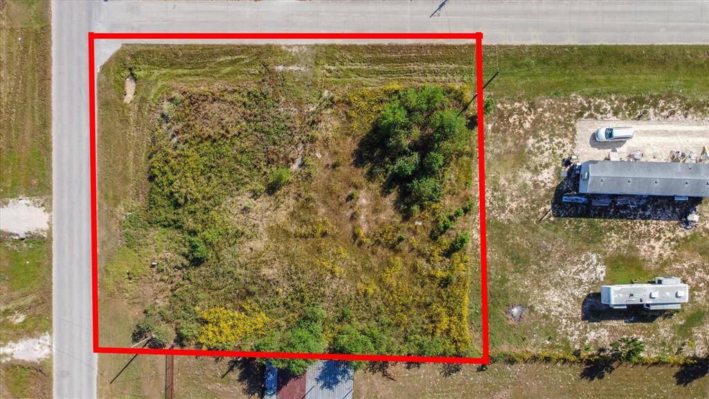 The terrain appears mostly flat and grassy, and the property is situated near paved roads with easy access to the surrounding neighborhood.