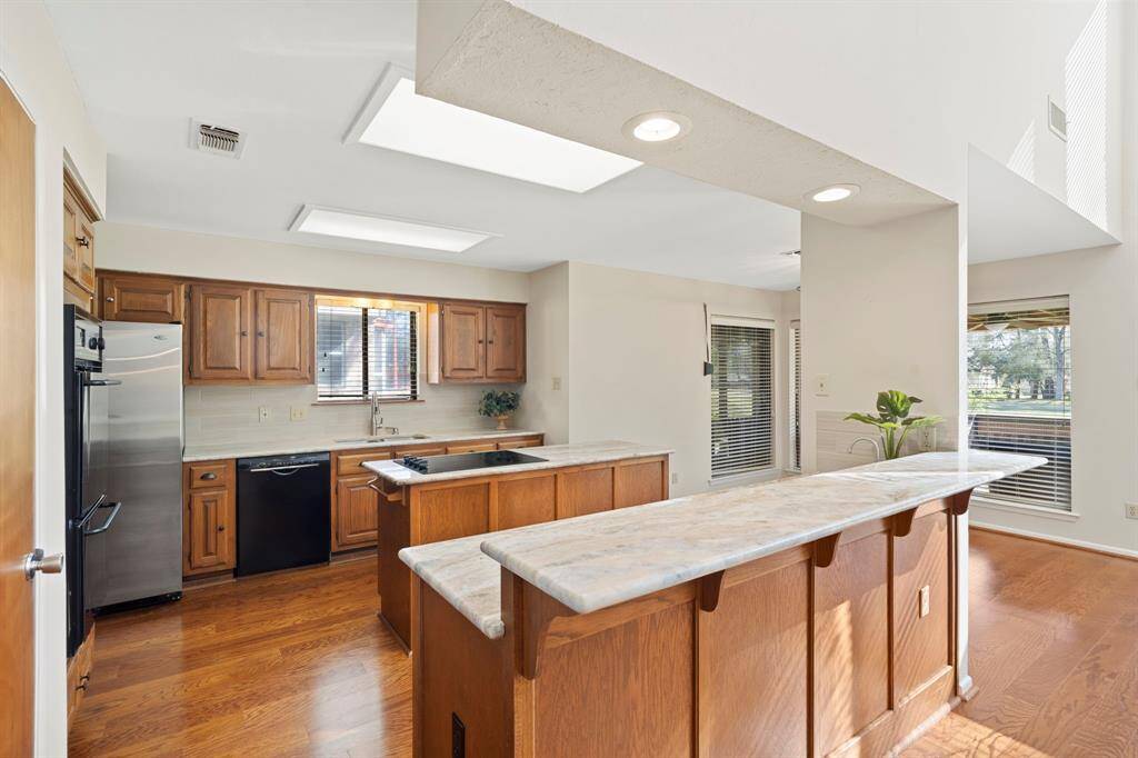Gorgeous light granite countertops with modern wood look tile backsplash.