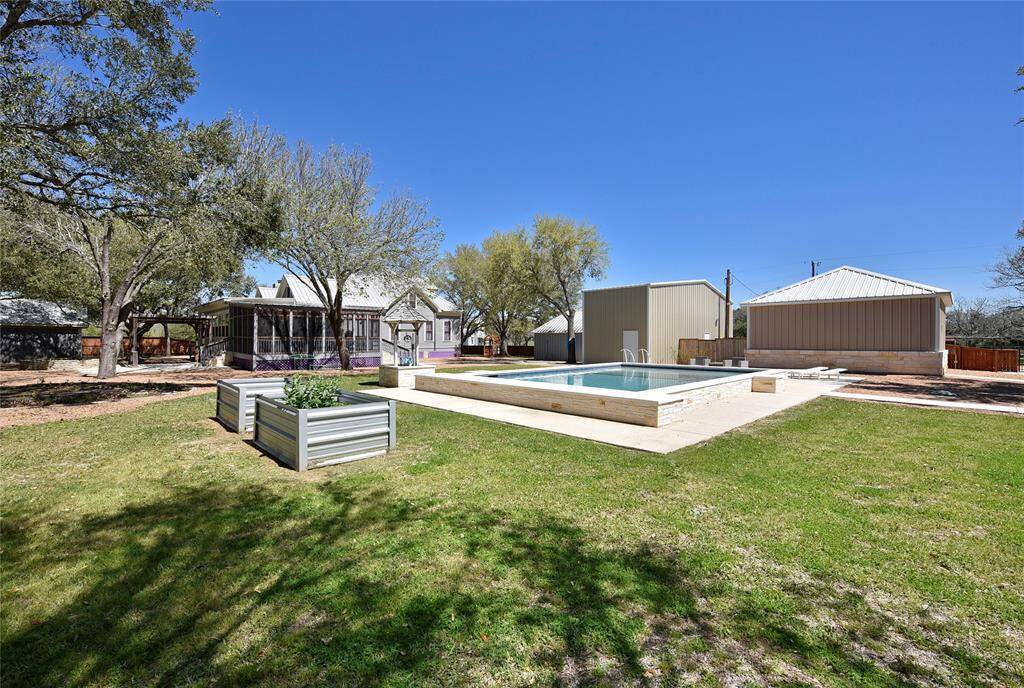 This view of the pool shows the raised planter beds. Behind the pool to the right is a oversized garage for the Guest house. In the middle is the RV garage and the the left of the RV garage is the craft house/workshop. The craft shop/workshop has its own central A/C unit.