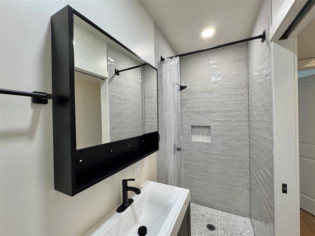Centrally located in the hallway, this secondary bath offers a marble-floored walk-in shower. There is ample storage in the mirrored cabinet.
