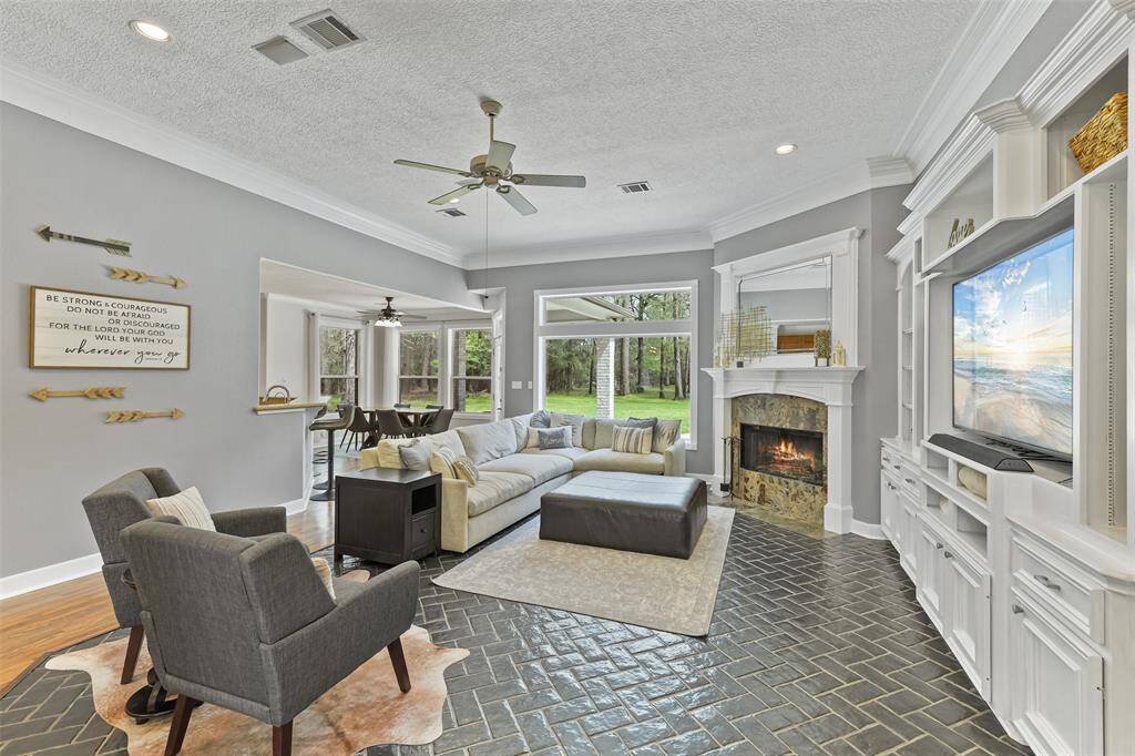 Welcome to a bright and inviting entryway leading into an open-plan living area with elegant wood and tile flooring. The space features a modern chandelier, a cozy fireplace, and large windows offering scenic views. Perfect for a comfortable and stylish lifestyle.