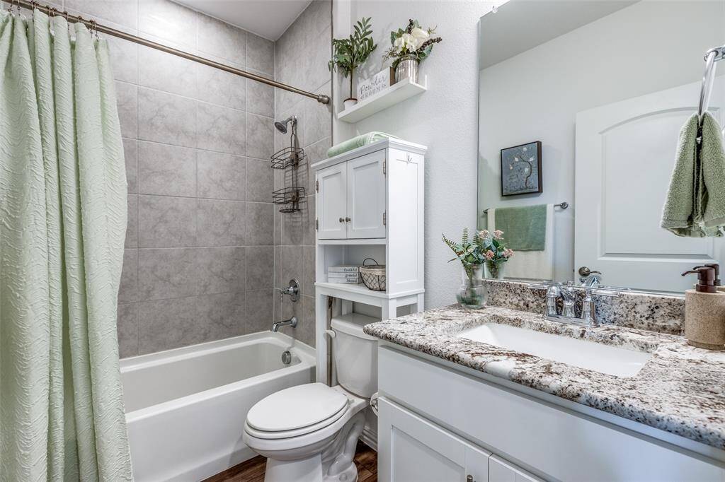 Full bathroom featuring shower / tub combo with curtain, wood finished floors, vanity, and toilet
