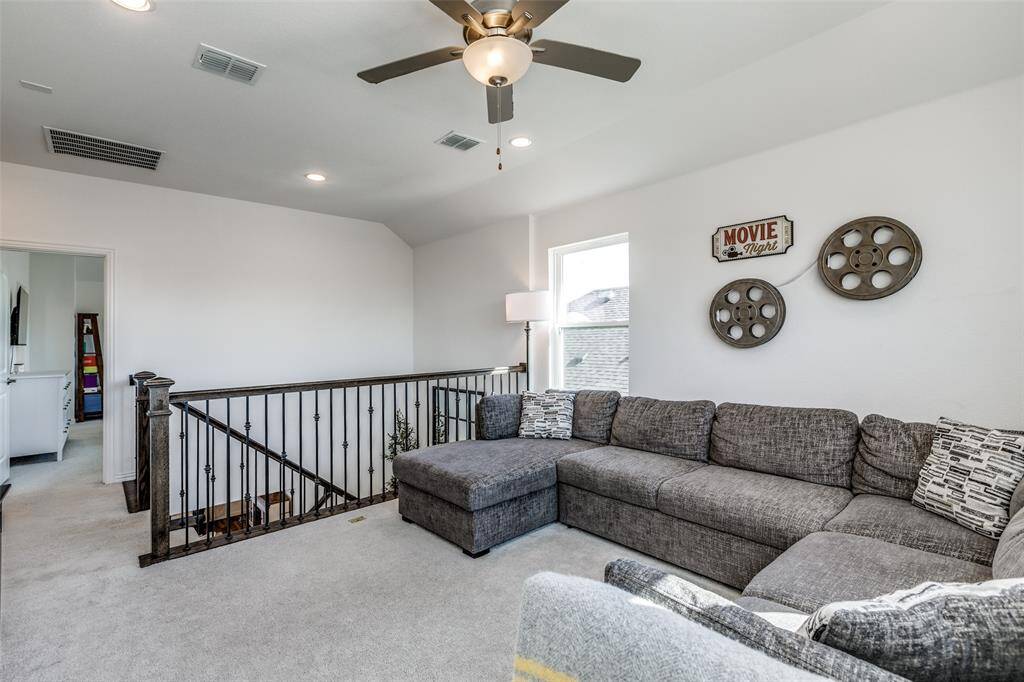Living room featuring visible vents, light colored carpet, lofted ceiling, and a ceiling fan
