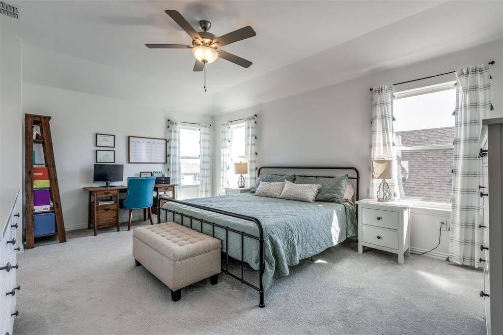 Bedroom featuring baseboards, light colored carpet, visible vents, and ceiling fan