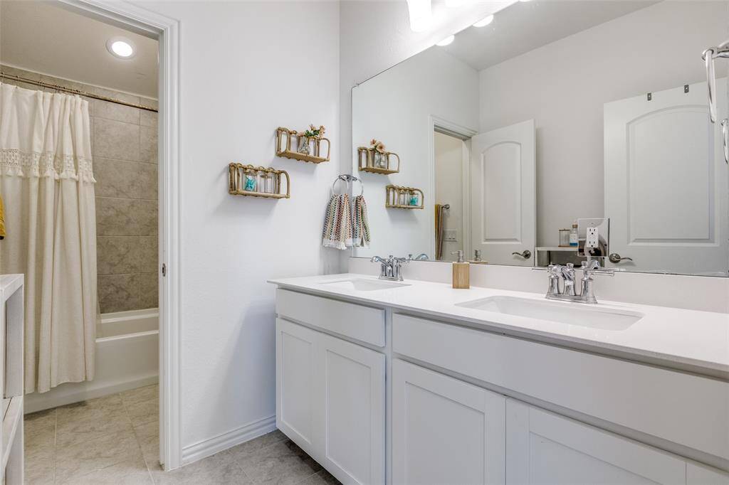 Bathroom with double vanity, tile patterned flooring, shower / tub combo with curtain, and a sink