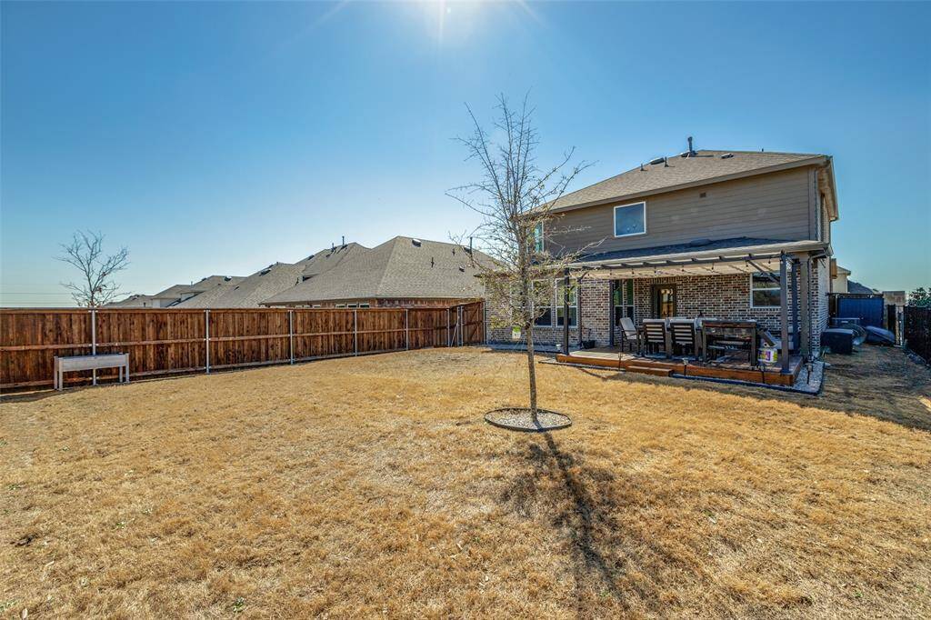 Rear view of property with brick siding, a patio area, a fenced backyard, and a lawn
