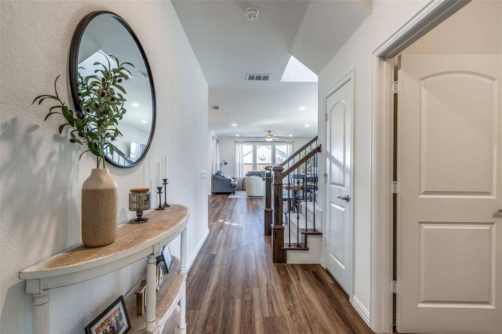 Hall with dark wood finished floors, stairs, and visible vents
