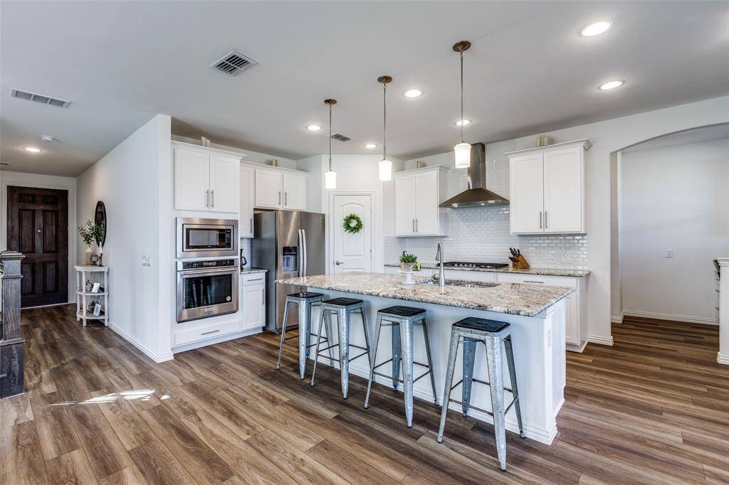 Kitchen with visible vents, a sink, stainless steel appliances, a kitchen breakfast bar, and wall chimney exhaust hood