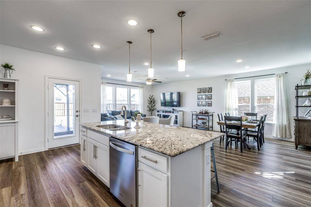 Kitchen with visible vents, dark wood-type flooring, decorative light fixtures, dishwasher, and a sink