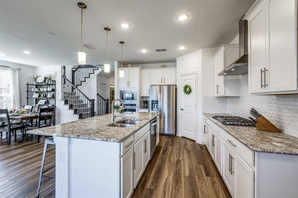 Kitchen featuring visible vents, appliances with stainless steel finishes, dark wood-style flooring, and wall chimney range hood