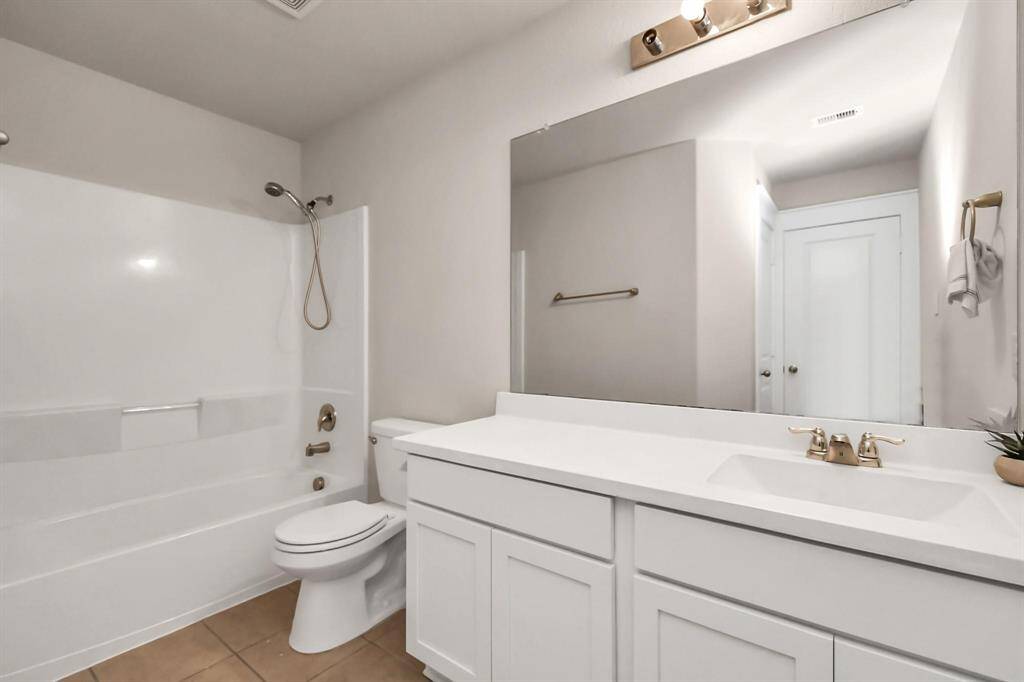This bathroom features a clean, modern design with a large mirror, a spacious vanity, and a bathtub-shower combo. The neutral tones and ample lighting create a bright and inviting space.