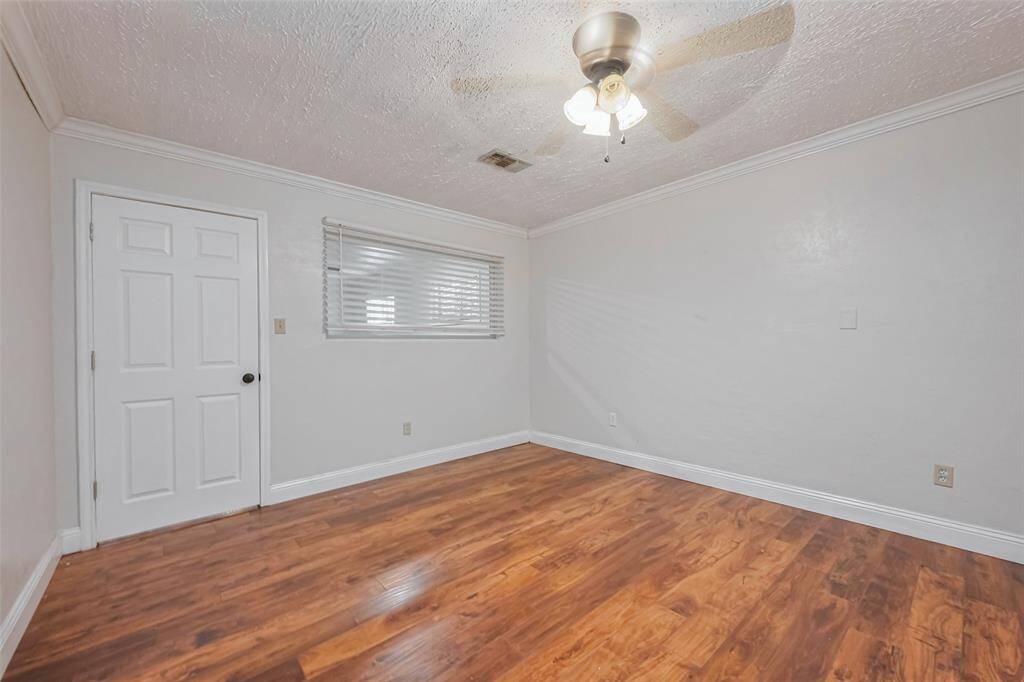 Featuring the same sleek wood-like flooring and a ceiling fan for added comfort, this room maintains a cohesive design with the rest of the home.