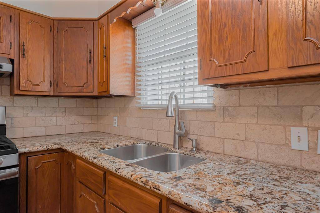 Situated below a window, the kitchen sink provides a bright workspace with a view. The stylish backsplash pairs perfectly with the granite countertops for a polished look.
