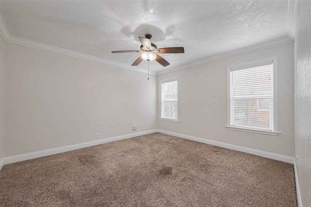 Soft carpeting enhances comfort in this generously sized bedroom, where white walls and ceilings maintain an airy and peaceful aesthetic.