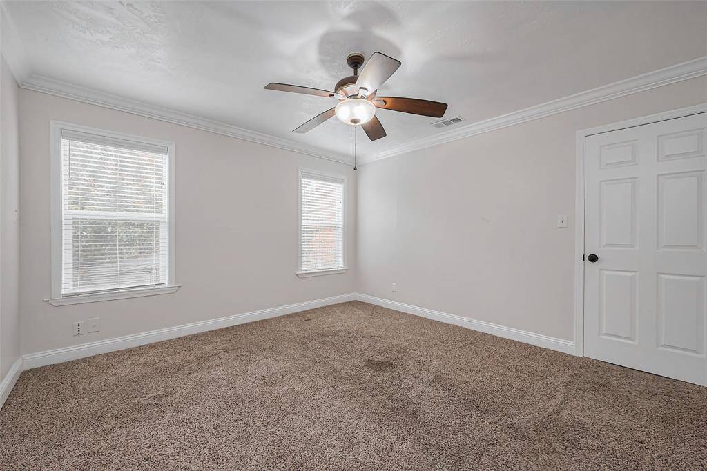 A ceiling fan adds comfort, while large windows fill the space with natural light, making it feel open and inviting.