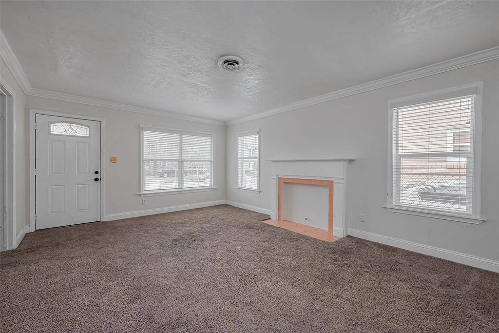The front door opens into a well-lit living area, where multiple windows bring in natural brightness.