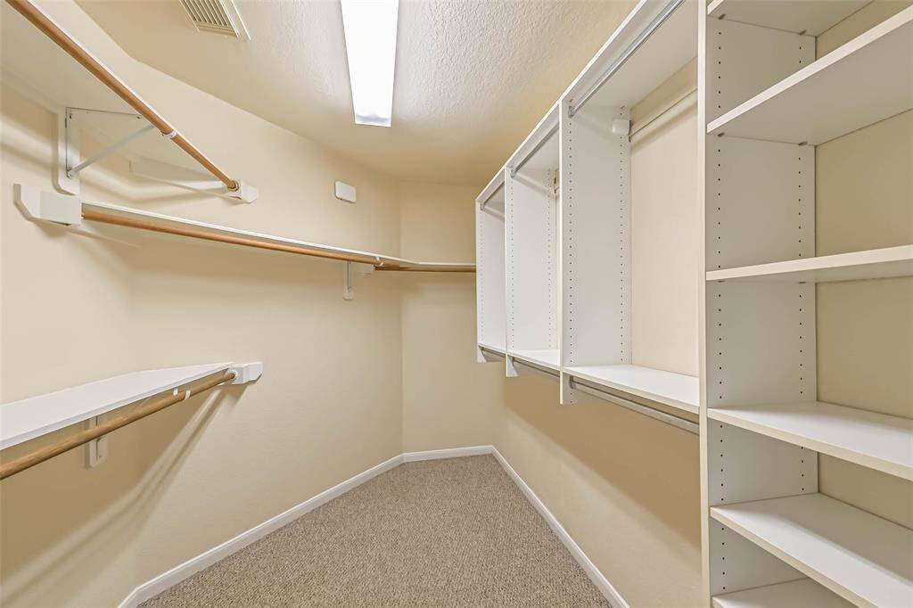 The primary walk-in closet offers plenty of space with hanging rods and built-in shelving, providing an organized and efficient storage solution. It’s designed to accommodate all your wardrobe needs, making it easy to keep everything neatly arranged and accessible.