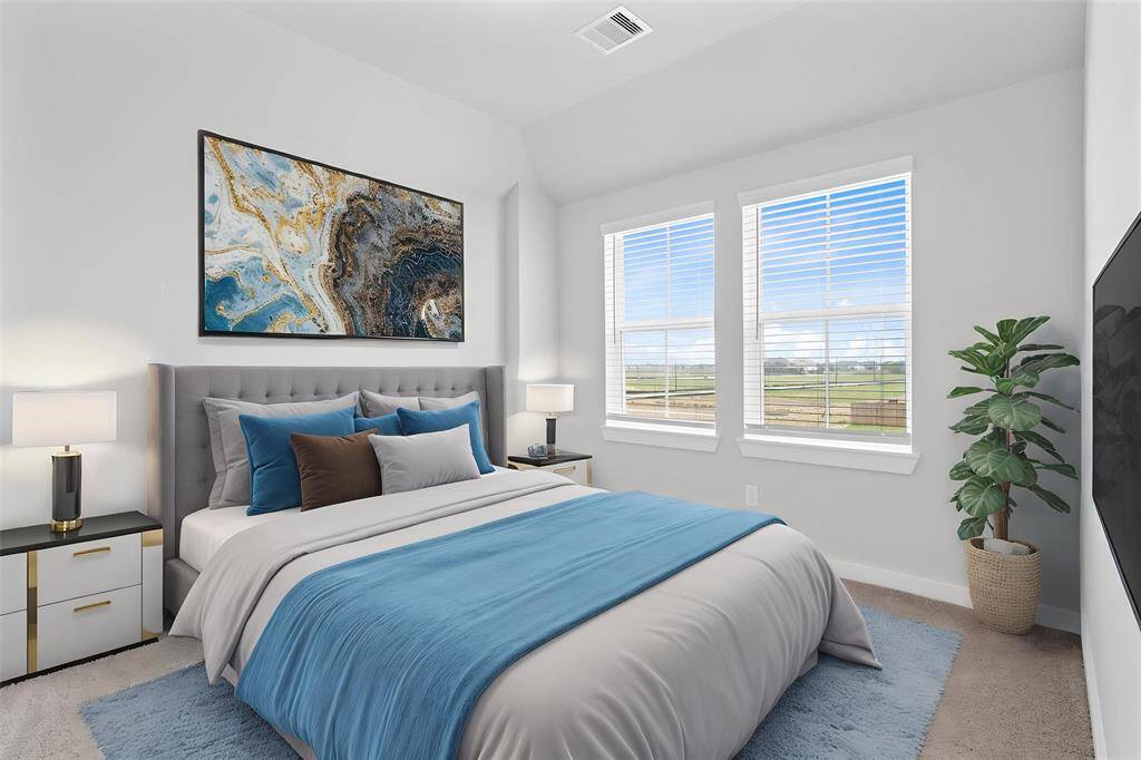 Secondary bedroom features plush carpet, neutral paint, lighting, closet space, and large windows with blinds.