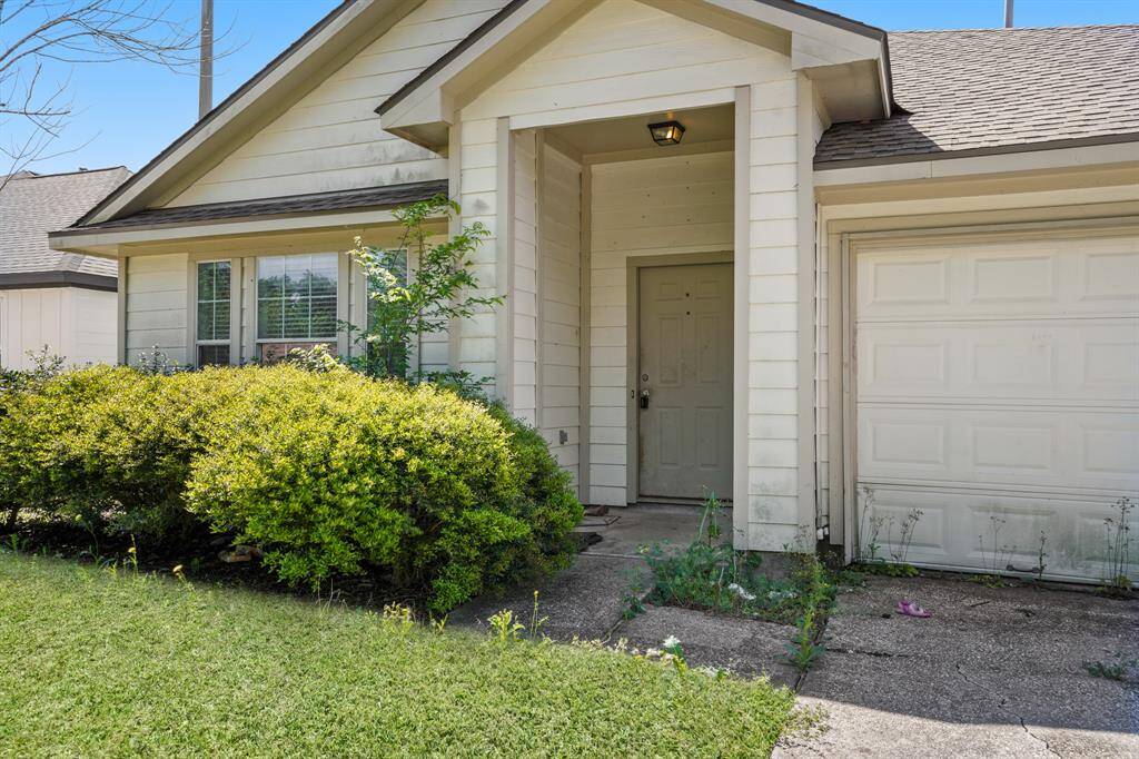 Charming single-story home with a welcoming front porch and attached garage. Features mature shrubs and a well-maintained lawn, adding to its curb appeal.