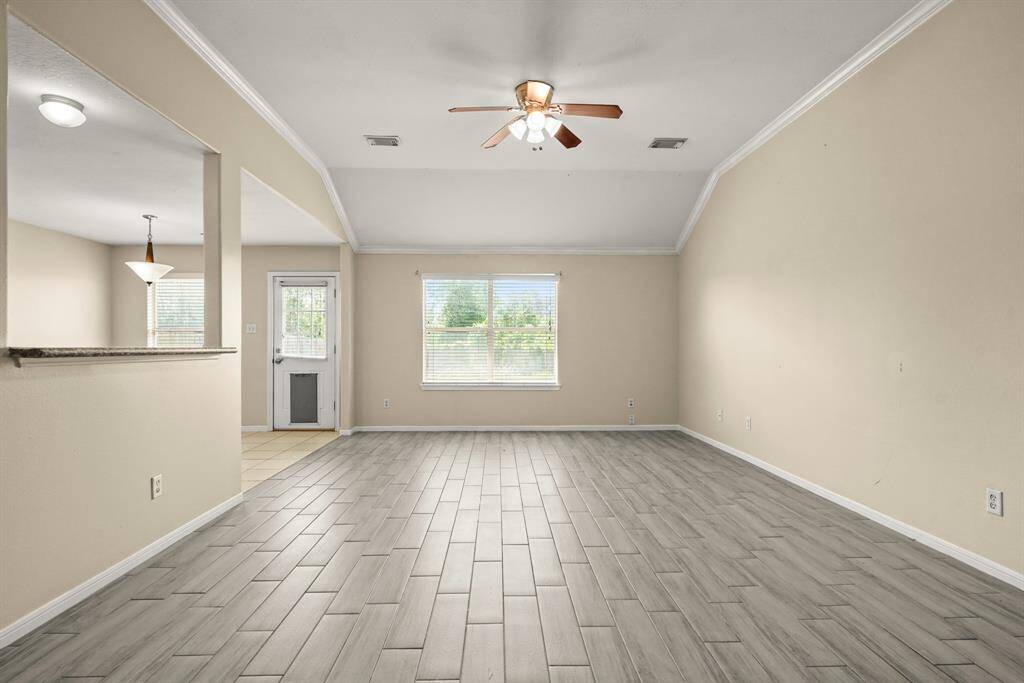 This spacious living area opens to the kitchen with a passthrough window and has a large window letting in natural light.